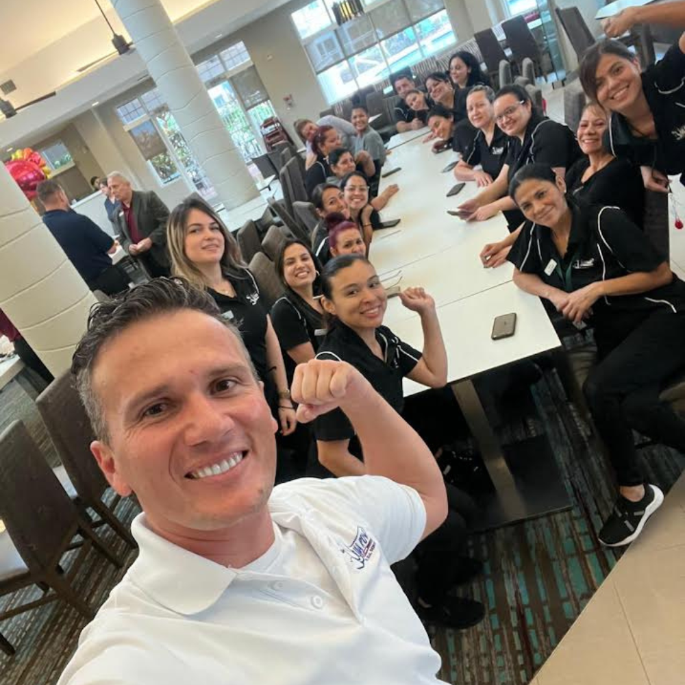 group of housekeepers sitting at a table while a supervisor in a white shirt holds the camera