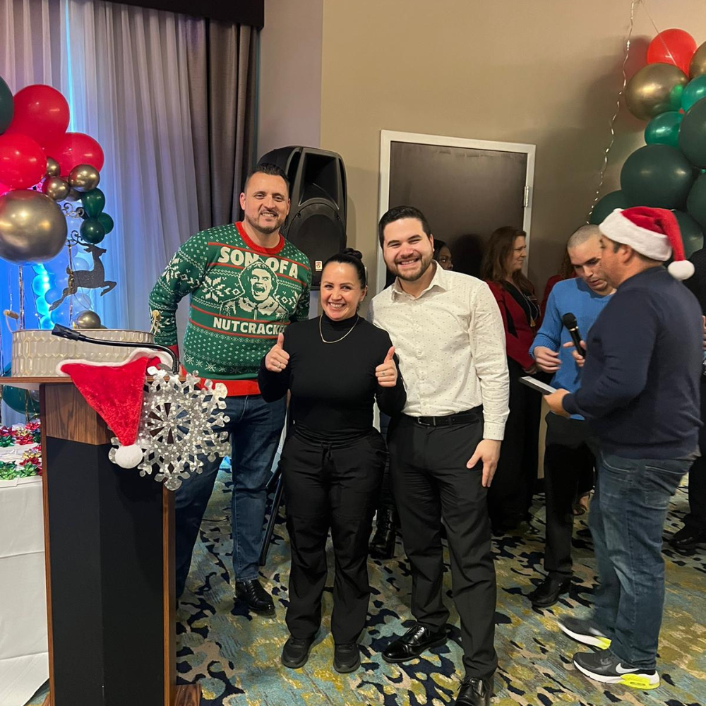 Staffing member wearing santa hats with balloons in background at holiday party